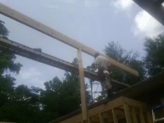 Carpenter setting a ridge beam over a new addition frame — Ice Dam Removal by Roofing Brothers in Bradner
