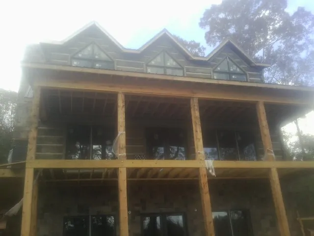 Dormers and porch framing on a large log home under construction — Roof Coating work by our crew in Bradner