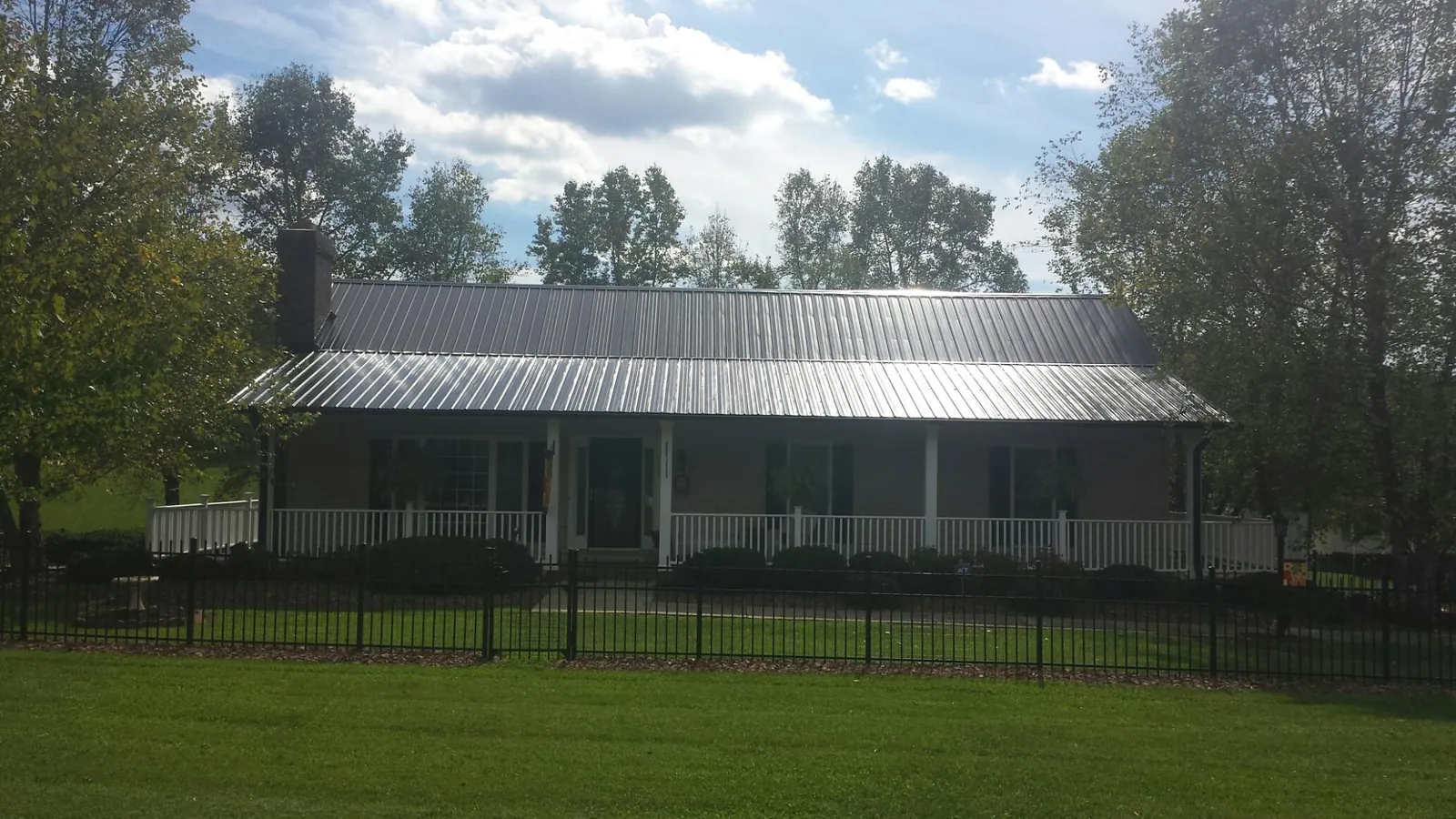 Gray metal roof on a brick ranch with a full width front porch — Gutter Guard Installation work by our crew in Bradner