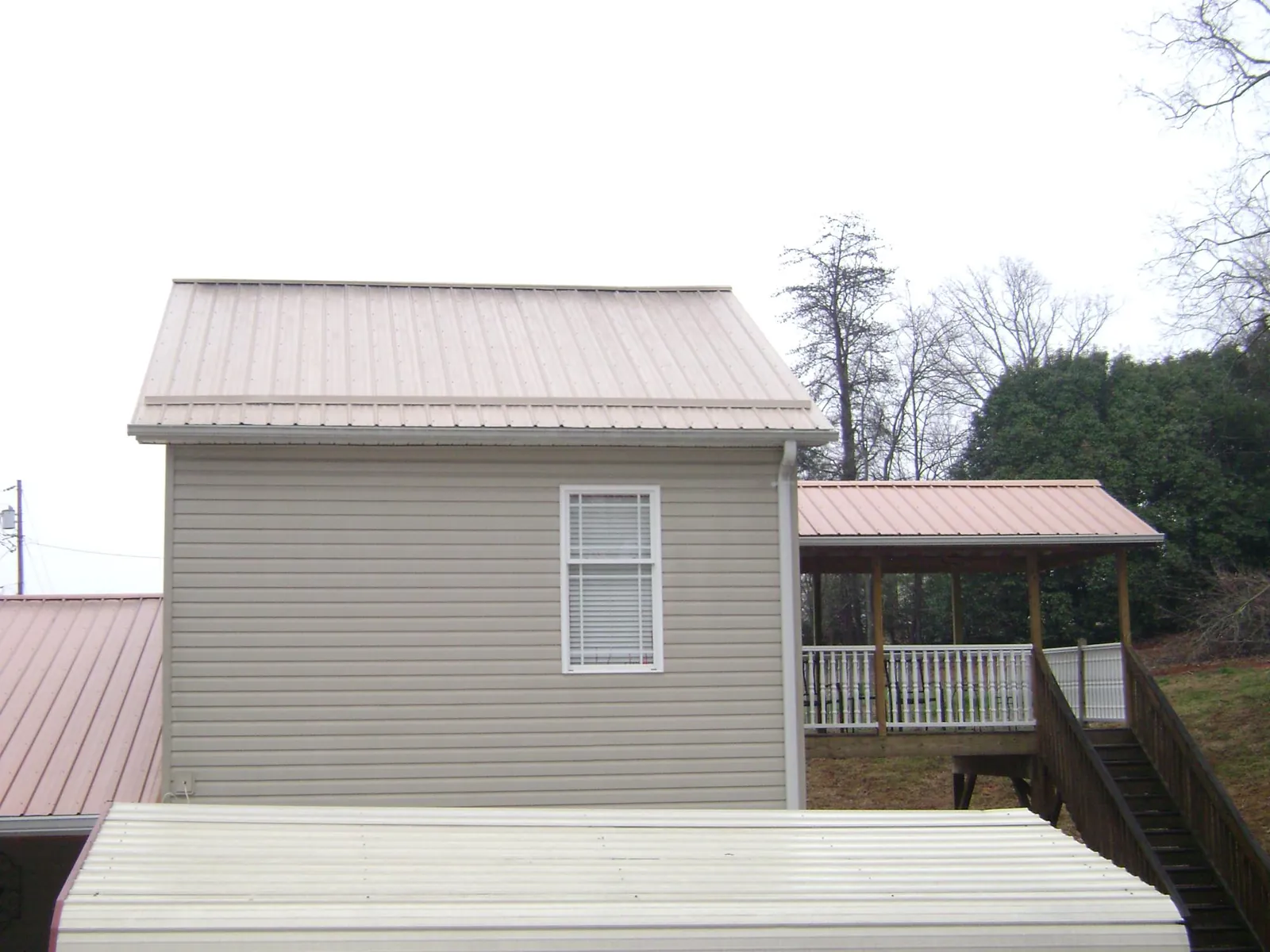 Tan metal roofs on a two story addition and attached porch, from a Roof Replacement job in Bradner