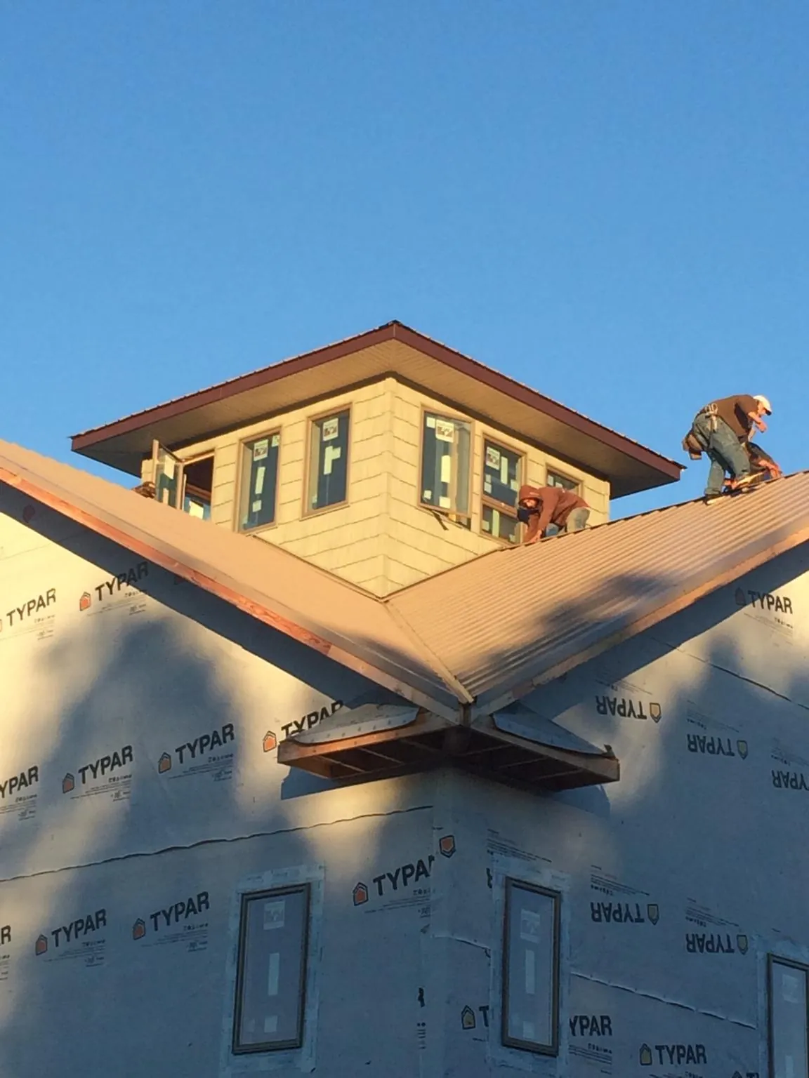 Roofers working around a rooftop cupola on a new metal roof at sunset — Roof Waterproofing in Bradner by Roofing Brothers